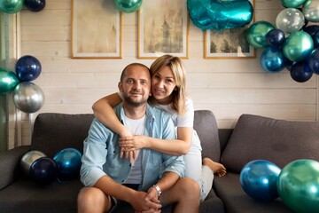 Couple celebrates special occasion in cozy indoor setting with colorful balloons and decorative...