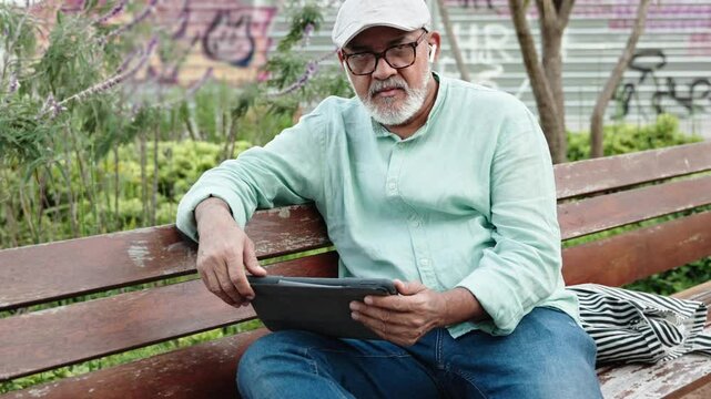Senior man using technology digital tablet in public park