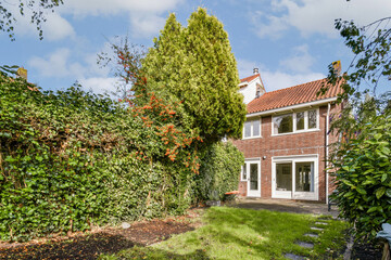 A picturesque house with a red tiled roof, nestled among vibrant trees and rich foliage, providing a serene outdoor environment.