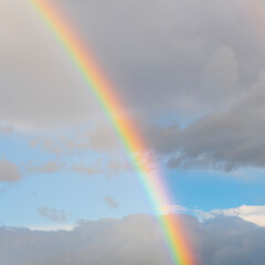 amazing bright rainbow in beautiful evening blue cloudy sky after rain and thunder with flash sun light streaming thruogh the clouds, weather thunderstorm concept