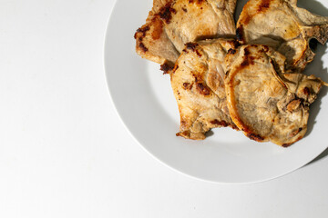 Grilled pork chops on a white plate, perfect for summer barbecues, family gatherings, rustic cooking, and comfort food