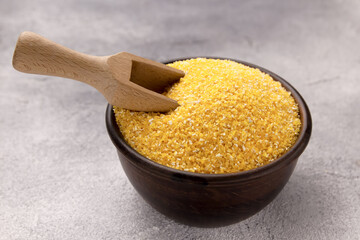Raw cornmeal in a bowl on a gray tiled table