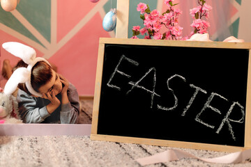 A little boy in a bunny costume in an Easter interior with decorative eggs and a bunny toy