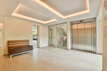 A spacious and well-lit modern entrance featuring a sleek elevator, comfortable seating, and contemporary design elements that create an inviting atmosphere.