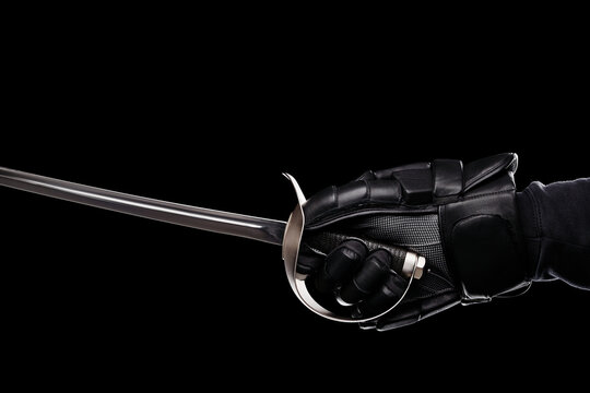 A gloved hand firmly grips the hilt of a sword, highlighting strength and readiness. The dark background enhances the focus on the sword and glove.