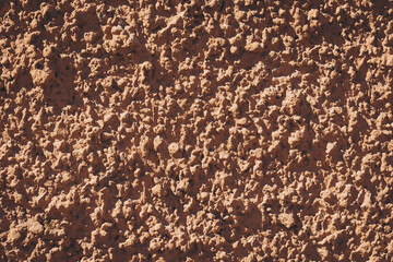 Rustic earthen wall texture captures the charm of traditional construction in a sunlit environment, showcasing the unique patterns and colors found in natural materials.