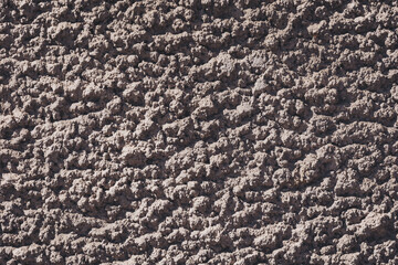 Gray stone grain texture background. Textured wall showcasing natural earthy tones and rugged surfaces under bright sunlight during a midday exploration in a historical setting