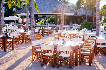 Beach restaurant with a bar and a number of fancy arranged client tables.