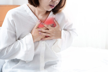 asian woman suffering from chest pain, possibly caused by heart problems, acid reflux, anxiety,...