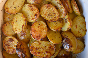 Baked potato halves with a crispy golden crust, seasoned with spices and drizzled with oil....