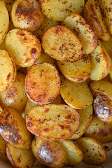 Baked potato halves with a crispy golden crust, seasoned with spices and drizzled with oil. Perfectly roasted potatoes, delicious comfort food, rustic cooking, side dish.