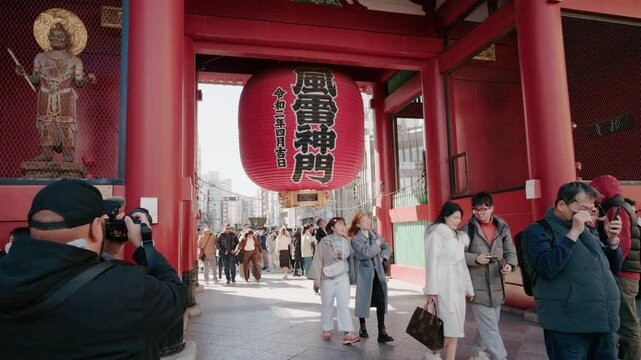 Tokyo, Japan - 15 Feb 2025 : 4K People and tourists crossing the street in front of Senso-ji Temple entrance in Tokyo, iconic Japanese landmark.