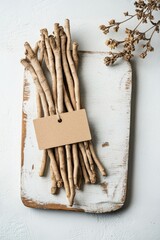 Photograph of ashwagandha roots with rustic tag and name, overhead flat-lay on white surface