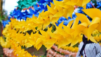 Colorful pinwheels in a row, yellow in focus. Fun, vibrant, and whimsical.