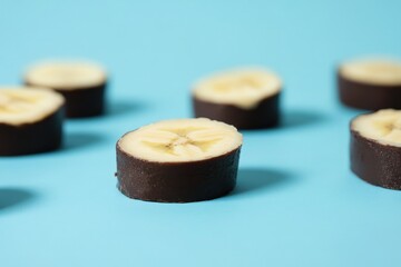 Slices of banana coated in dark chocolate on a blue surface