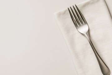 Elegant fork resting on neatly folded napkin against minimalist