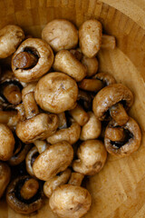 Marinated champignon mushrooms in a wooden bowl, ready for grilling. Fresh, rustic ingredients for outdoor BBQ. Natural light, healthy plant-based cooking scene.