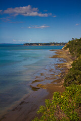 A picturesque coastal view from St Heliers, Auckland, with lush green cliffs descending to a rocky...