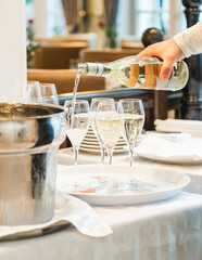 Restaurant. The waiter pours white wine into the glasses