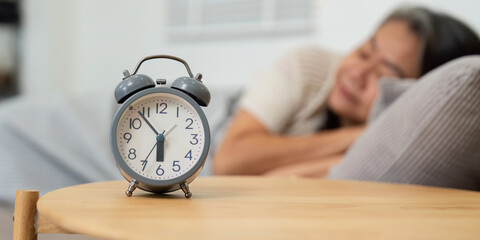 Sleep Routine and Wellness. An alarm clock signals time for rest in an elderly woman's daily...