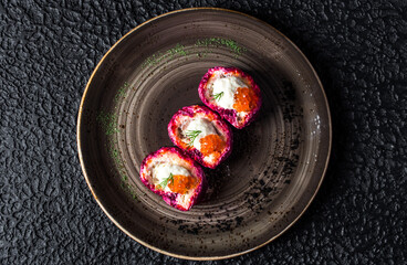 Beetroot Caviar Sushi Rolls in black plate on black background.