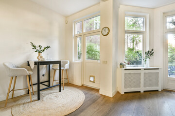 A stylishly designed indoor space featuring a small table, stools, and plants with ample natural...