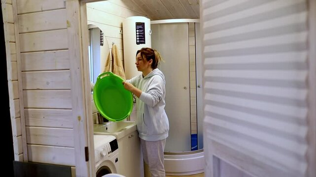 Woman performs laundry duties in a small, cozy laundry room at home