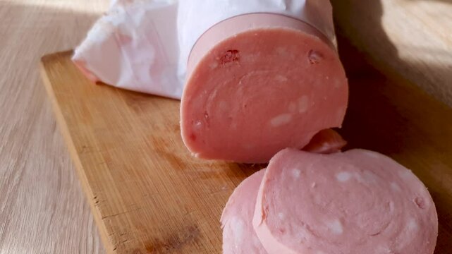 Milk sausage, slicing sausage on a board with a knife. Cutting sausage.