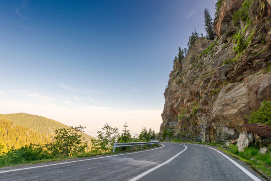 transfagarasan road curve near steep rocky slope. great outdoors of fagaras mountain ridge of romania in summer. dangerous alpine pass in carpathians. popular travel destination of europe