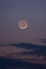 A stunning young moon illuminating the sky above the clouds