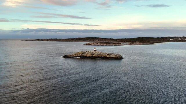 view of a sea mark on top of the rocky islet of Galten in Sveggevika bay under partly cloudy sky