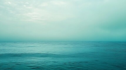 Fototapeta premium Calm teal ocean under a hazy sky.