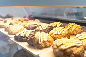 Freshly baked cookies and scones, decorated with icing and pistachios, sit on display in a bakery window, tempting customers with their sweet aroma