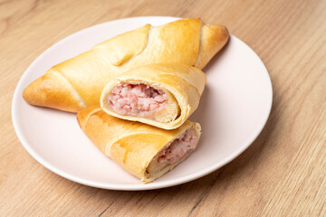 Freshly baked ham and cheese croissants resting on a pink plate, showcasing their golden-brown crust and savory filling