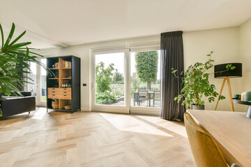 A contemporary living room featuring large windows, stylish furniture, and vibrant indoor plants, creating a bright and welcoming atmosphere.