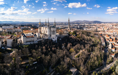 Obraz premium Aerial panoramic view of the Basilica of Notre-Dame de Fourvière on Fourvière Hill in Lyon, France, with cityscape and metallic tower in the background on a clear sunny day