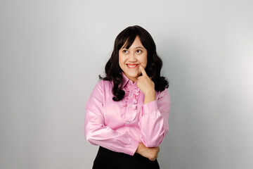 Fototapeta premium Asian woman with cheerful and smiling face wearing pink shirt shows gesture of imagining something beautiful or pleasant.