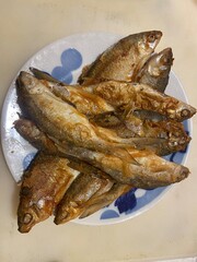 Crispy fried whole fish on a traditional patterned plate – golden brown seafood dish