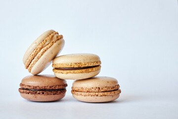 Four brown French Macarons, cakes with different flavors, coffee and creme brulee flavor. pyramid of homemade dessert, macaroons side view