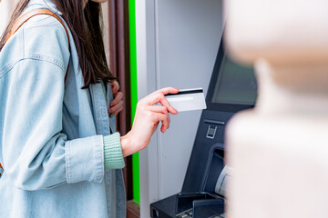 Student using a credit card for cash withdrawal at an automated teller machine, engaging in a...