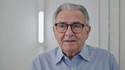 Older man wearing glasses and blue shirt in formal setting