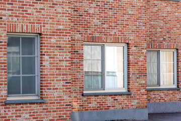 Clay brick building with three windows, windows in a red brick building, the front of a house with...