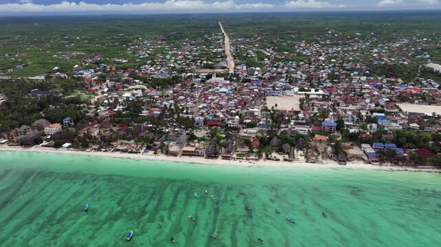 4k aerial video footage - flying along Paje white sand Beach - located on island of Unguja, part of Zanzibar in Tanzania, during hide tide  with City of Paje and countryside landscape in background 