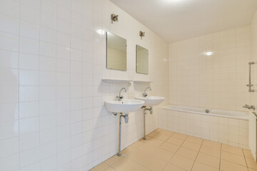 A contemporary bathroom featuring clean lines, white tiles, dual sinks, and a bathtub, creating a minimalist and spacious atmosphere.