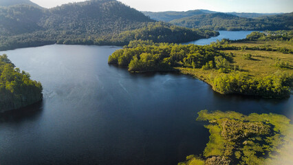 Dark lakes between the mountains of Tasmania on a sunny day, seen from above