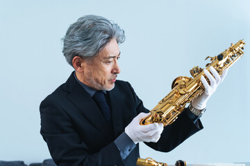 サックスを確認するミドルエイジ男性　鑑定士・リペアマン・楽器職人