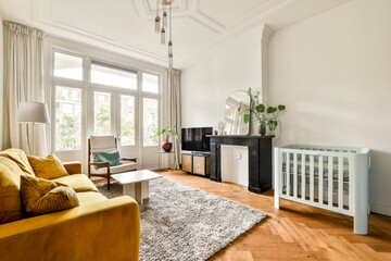 A modern living room featuring a cozy ambiance, yellow sofa, light colors, wooden flooring, and a baby crib, ideal for family living spaces.