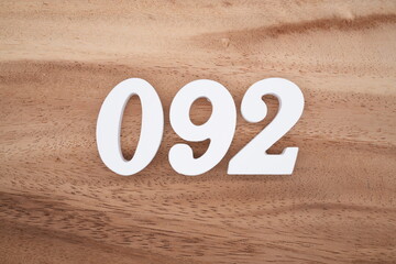 The numbers are made of white painted wood placed on a brown wooden floor.