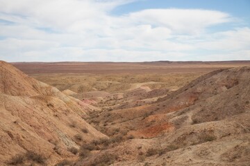 Fototapeta premium desert landscape; arid terrain; barren hills; natural erosion; remote wilderness; dry valley; colorful desert; steppe region; semi-arid environment; geological formations; earth tones; rugged nature; 