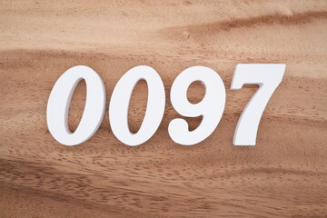 The numbers are made of white painted wood placed on a brown wooden floor.